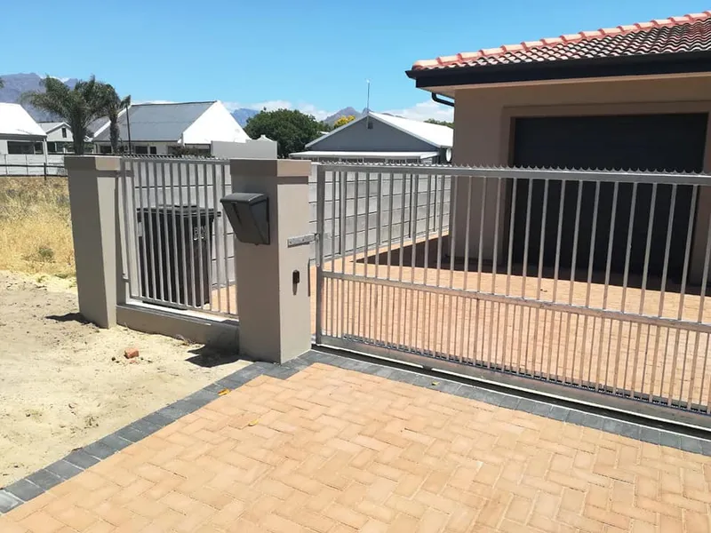 Palisade sliding gate and pedestrian gate on paved driveway